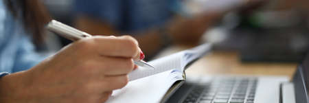 Female hand holds pen with notebook closeupの写真素材