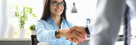 Businesswoman smiles and shakes hands with her partnerの写真素材