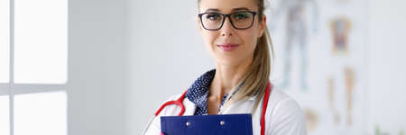 Medical officer smiles and holds clipboard in his hands.の写真素材