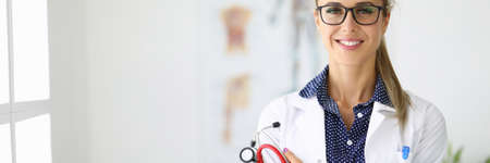 Female doctor in medical office is holding a stethoscope and smilingの写真素材