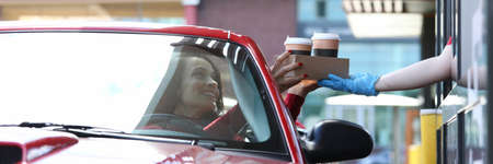 Woman in car picks up her coffee conceptの素材 [FY310156729025]