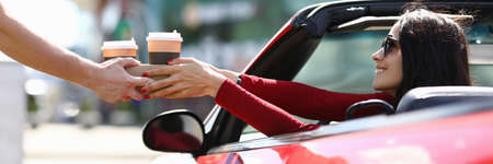 Courier hands over coffee to woman in car closeupの写真素材
