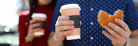 Man and woman are holding coffee and hamburgerの写真素材