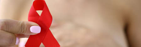 Female hand holds red ribbon on the background of chest.の写真素材