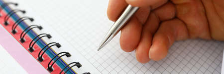 Mans hand holds pen on blank notebookの写真素材