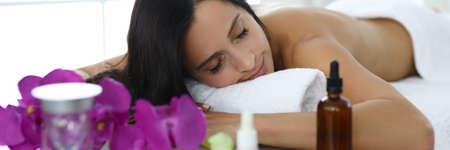 Woman lies with her eyes closed on massage tableの写真素材