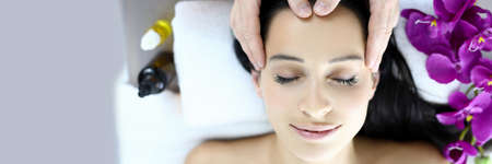 Massage therapist makes woman on massage table an acupressure head massageの写真素材