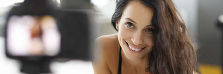 Woman lies on the bed in bra and records video on camera.の写真素材