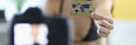 Woman in lingerie holds out bank card to camera.の写真素材