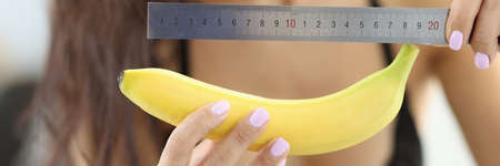 Woman in underwear holds banana and ruler.の写真素材