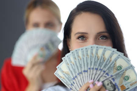 Portrait of a successful businesswoman holding american dollars in hands in front of her faceの写真素材