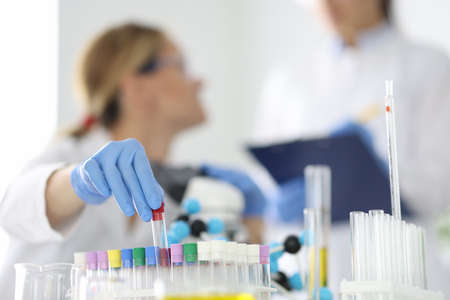 Laboratory diagnostics doctor holds glass test tube in rubber glove closeupの写真素材