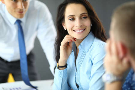Young business woman in blue shirt communicates with two men in office portraitの写真素材
