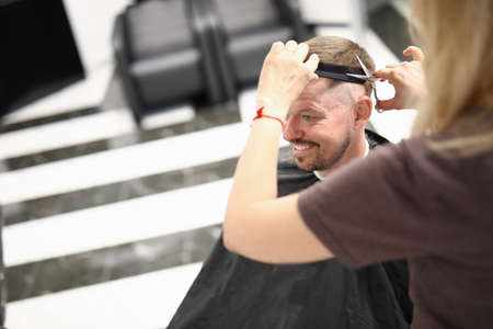 Young handsome smiling man sitting in hairdressing chair and doing wash portraitの写真素材