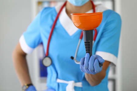 Nurse with stethoscope around neck in rubber gloves holds plunger closeupの写真素材