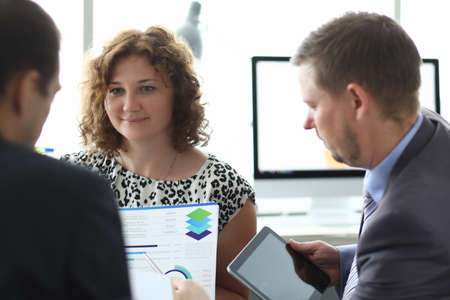 Business men and woman examine document with graphs and charts with tablet in hand portraitの写真素材