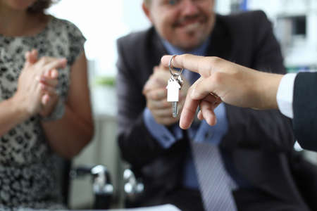 Husband and wife receive key to apartment from seller in office closeupの写真素材
