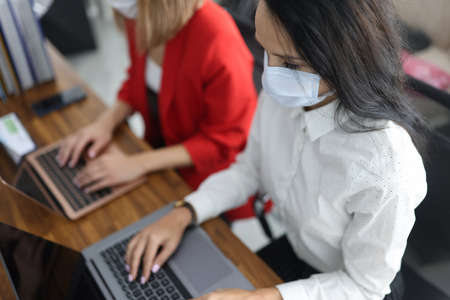 Business women in protective medical mask on face work at laptop in officeの写真素材