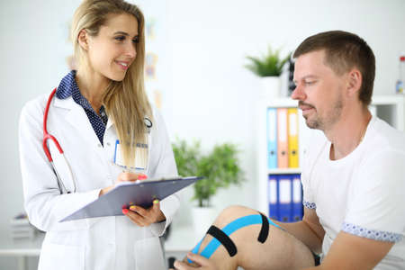 Female doctor writes down patients symptoms on clipboardの写真素材