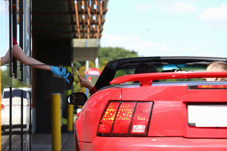Woman in car pays with a bank card in fast food cafe.の写真素材