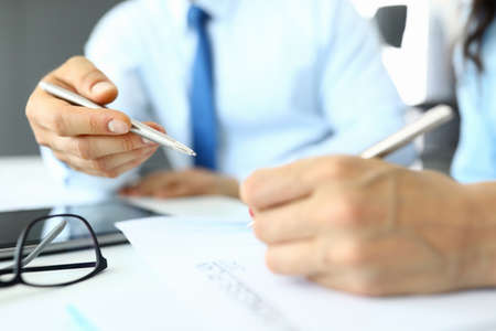 Male and female hands hold pens and write in documents.の写真素材