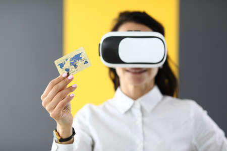 Woman is wearing virtual reality glasses in her hands she is holding bank credit cardの写真素材
