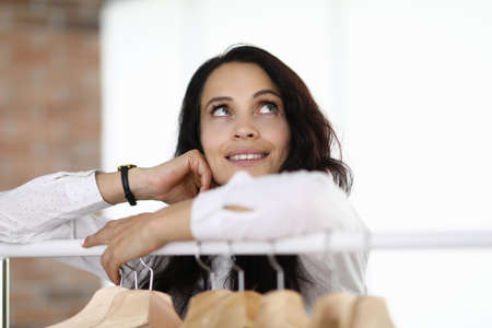 Woman stands with her elbows on hanger and looks up dreamily.の写真素材