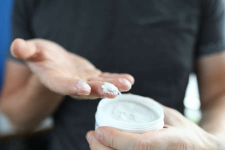 Mans hand holds jar with a white substance inside.の写真素材