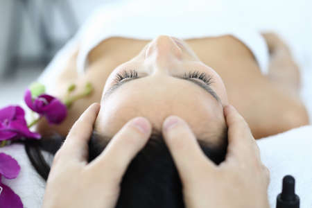 Masseurs fingers lie on womans face closeupの写真素材