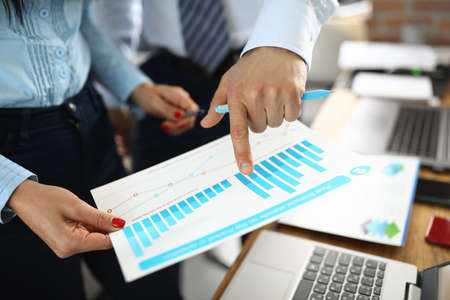Male and female hand holding charts with business indicators in office.
