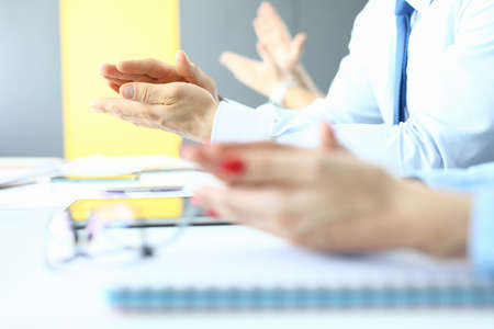 Womens and mens applaud at work table in office.