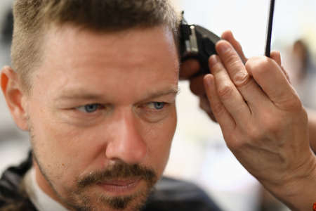 Portrait of man whose stylist cuts with hair clipper.の写真素材