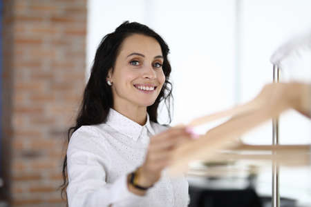 Smiling brunette woman holding empty hangers hand.の写真素材