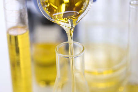 Golden liquid is poured from flask into test tube.の写真素材