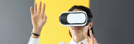 Young woman touches air with her hands in virtual reality glassesの写真素材