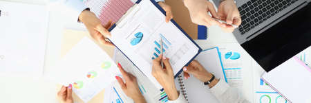 Group of business people men and women sit at table in office with papers, laptop and phone top viewの写真素材