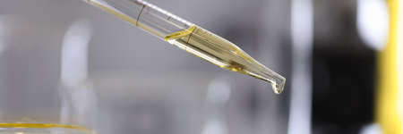 Drop of oil drips from dispenser into petri dish in chemical laboratory closeupの写真素材