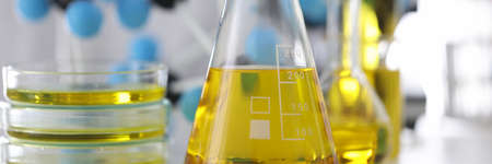Scientist in rubber gloves holds glass flask with yellow liquid in chemical laboratory closeupの写真素材