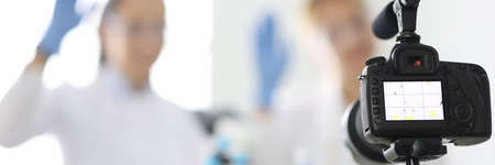 Camera captures female chemist bloggers who are waving in chemical laboratory closeupの写真素材