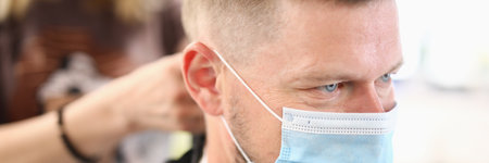 Man in protective medical mask has haircut in hairdresserの写真素材
