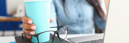Female hand holds cup of coffee at workplace.の写真素材