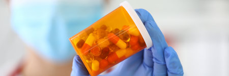 Smiling doctor in protective mask holds jar of pills.の写真素材