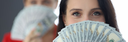 Portrait of a successful businesswoman holding american dollars in hands in front of her faceの写真素材