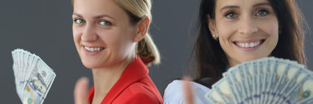 Two women stand with bundle of money and show thumb gesture portraitの写真素材