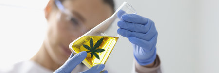 Woman in rubber gloves holding glass flask with hemp extract closeupの写真素材