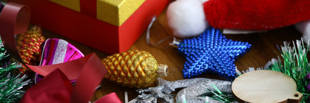 Christmas tree toys, red santa claus hat, tinsel and other decorations lie on table close-upの写真素材