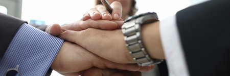 Businesswoman and two businessmen folded their hands together in office closeupの写真素材