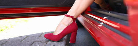 Womans leg in red shoe is exposed from red car.の写真素材