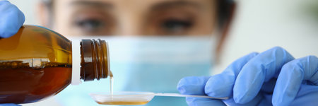 Doctor pours medicine into measuring spoon closeup