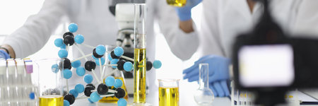 Scientists at work table on which flasks and molecules are filming experiments on video cameraの写真素材